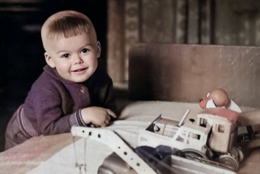 Oturma odasında oyuncak arabalarla oynayan küçük bir çocuğun klasik portresi. Şirin bir çocuğun komik fotoğrafı. 1970 'lerden kalma eski bir fotoğraf..