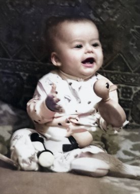 Tatlı, gülümseyen bir çocuğun klasik portresi. Çocuk yatağında oturuyor ve bir oyuncak tutuyor. 1968 'den eski bir fotoğraf.