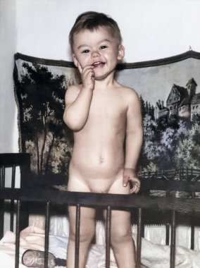 Beşiğinde duran bir çocuğun klasik portresi. Çocuk gülümsüyor. 1969 'dan kalma eski bir fotoğraf.