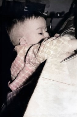 Masaya ulaşıp orada ne olduğunu görmeye çalışan meraklı küçük bir çocuğun klasik portresi. Retro fotoğraf, 1969.