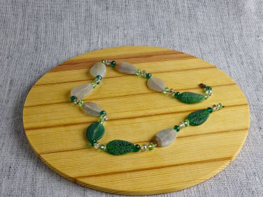 Doğal yeşilden yapılmış el yapımı boncuklar ve ahşap arka planda çatırtı etkisi olan mat beyazı..