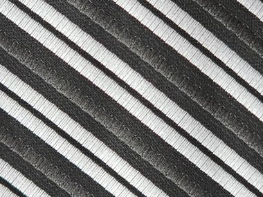 Çapraz siyah ve gümüş çizgili bir erkek kravatının kumaşı. Suç ortağı mikrofiberden yapılır..