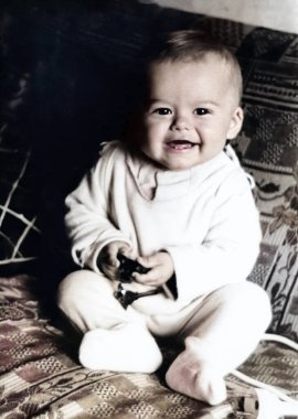 Yatağında oturmuş elinde oyuncakla gülümseyen küçük bir çocuğun klasik portresi. 1968 'den eski bir fotoğraf.