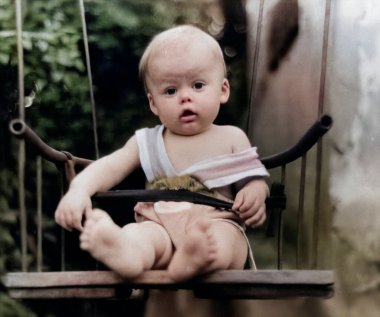 Bahçedeki iplerle asılı bir salıncakta sallanan bir çocuğun klasik portresi. Fotoğraf: 1968.