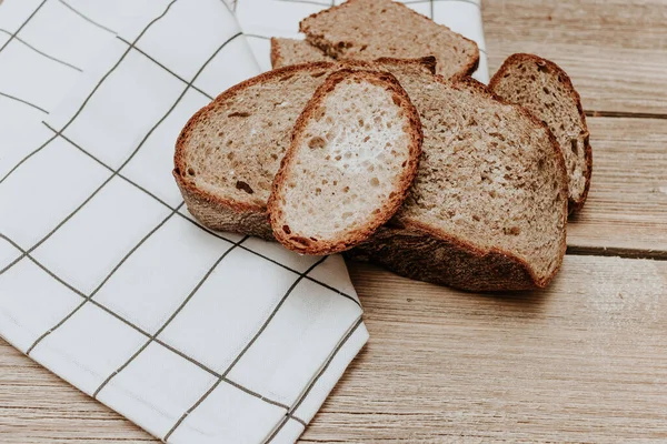 Bread on wood background. Sourdough bread cut into slices fall on old wooden surface in slow motion. Freshly baked bread