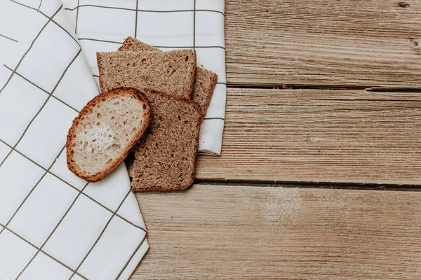 Bread on wood background. Sourdough bread cut into slices fall on old wooden surface in slow motion. Freshly baked bread