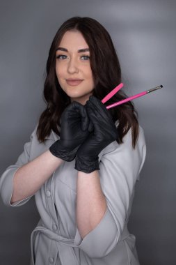 Güzel genç kız kirpik uzatma ustası. Kirpik için özel aletleri olan usta bir kozmetikçi. Kirpik uzatma prosedürü. Güzellik fotoğrafçılığına hazırlık. Bir resim oluşturuluyor.