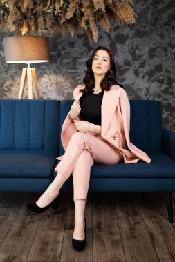 Kanepede güzel bir esmer. Güzel esmer, evde dizüstü bilgisayar ve telefon kullanıyor.