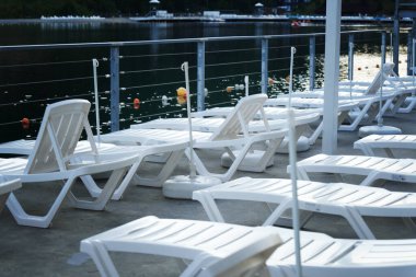 Adirondack sandalyeleri yazın çam ağaçlarına ve dağlara bakan gölün kenarındaki çimlerde.