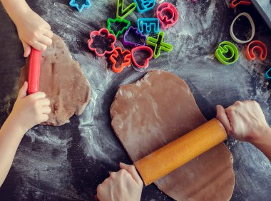 Anne ve kızı mutfakta birlikte oklava kullanarak