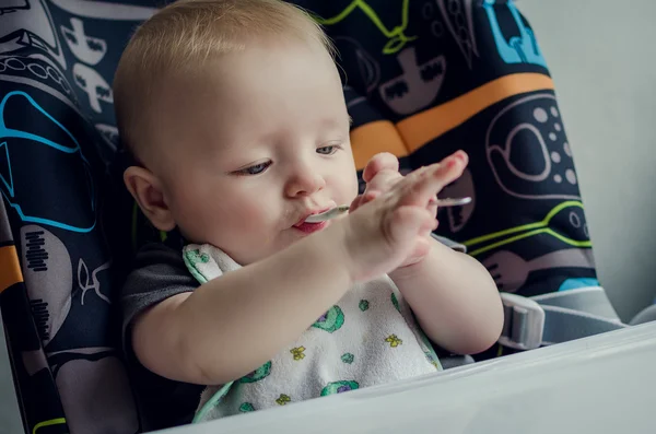 Adorable baby learning to feed himself for the first time