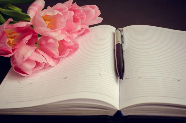 Schöne rosa Tulpen mit einem Notizbuch — Stockfoto
