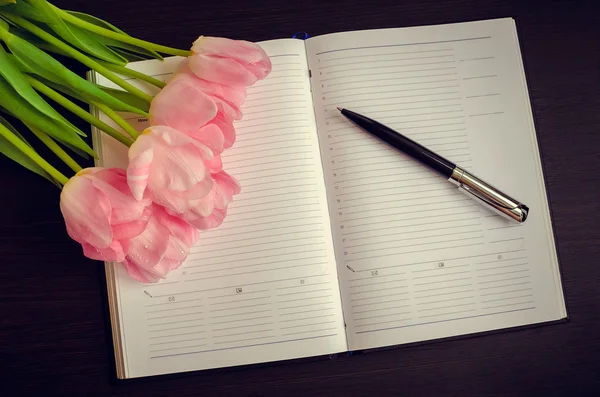 Schöne rosa Tulpen mit einem Notizbuch — Stockfoto