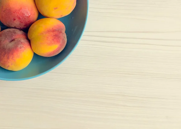 Ripe peaches in blue bowl