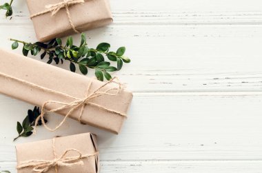 Modern Noel hediyeleri beyaz ahşap arka planda doğal dekor ile paketlenmiş. El sanatları kağıdında sicim ve yeşil dallarla kutular. Mevsimlik tebrik kartı. Üst Manzara. Düz yatıyordu. Boşluğu kopyala.