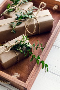 Modern Noel hediyeleri beyaz ahşap arka planda doğal dekor ile paketlenmiş. El sanatları kağıdında sicim ve yeşil dallarla kutular. Mevsimlik tebrik kartı. Üst Manzara. Düz yatıyordu.