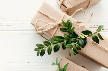 Modern Noel hediyeleri beyaz ahşap arka planda doğal dekor ile paketlenmiş. El sanatları kağıdında sicim ve yeşil dallarla kutular. Mevsimlik tebrik kartı. Üst Manzara. Düz yatıyordu. Boşluğu kopyala.