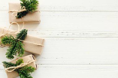 Modern Noel hediyeleri beyaz ahşap arka planda doğal dekor ile paketlenmiş. El sanatları kağıdında sicim ve yeşil dallarla kutular. Mevsimlik tebrik kartı. Üst Manzara. Düz yatıyordu. Boşluğu kopyala.