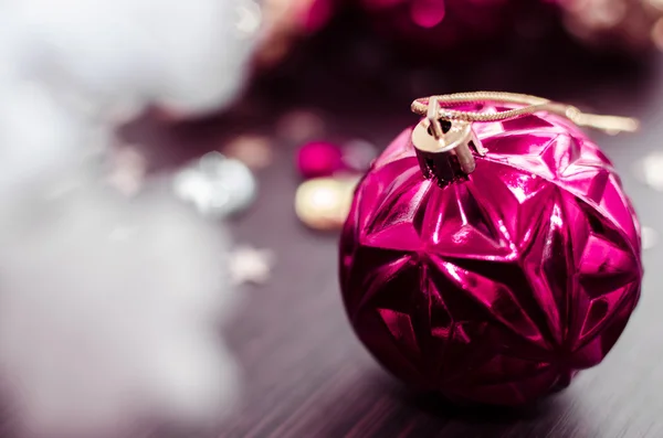 Magenta christmas ball on bokeh background of xmas ornaments. — Stock Photo, Image