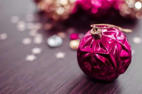 Magenta christmas ball on bokeh background of xmas ornaments. — Stock Photo, Image