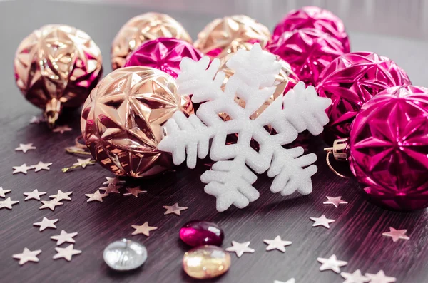 White snowflake on background of magenta and gold xmas baubles. — Stock Photo, Image