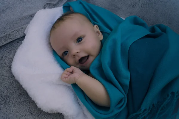 Bambino sorridente coperto di coperta blu — Foto Stock