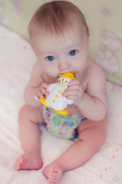 Beautiful baby boy sitting and sucking on his toy — Stock Photo, Image