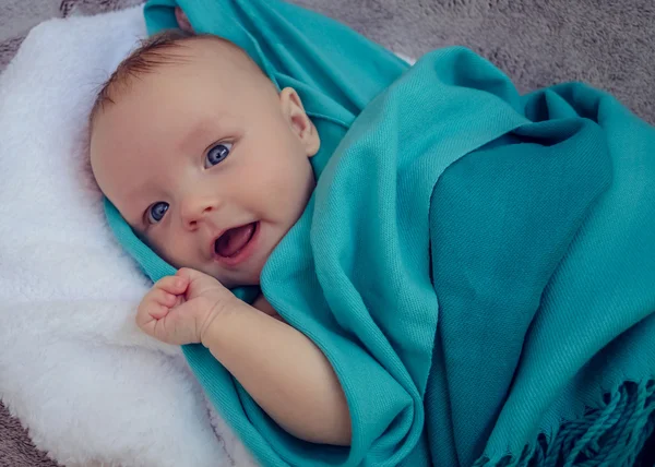 Glimlachende baby bedekt met blauw deken — Stockfoto