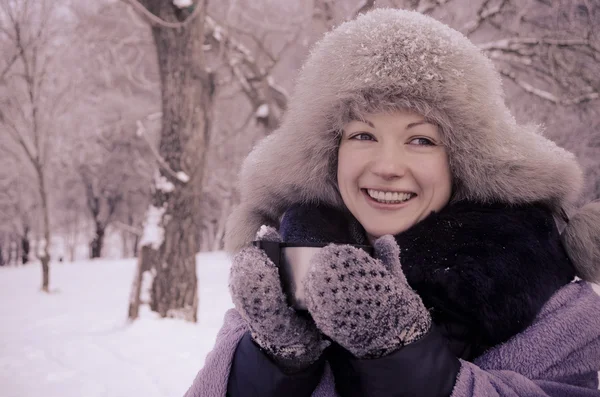 Smiling woman holding a travel mug in winter Stock Picture