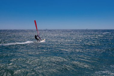 Rüzgar sörfçüleri deniz dalgalarında sörf yapar