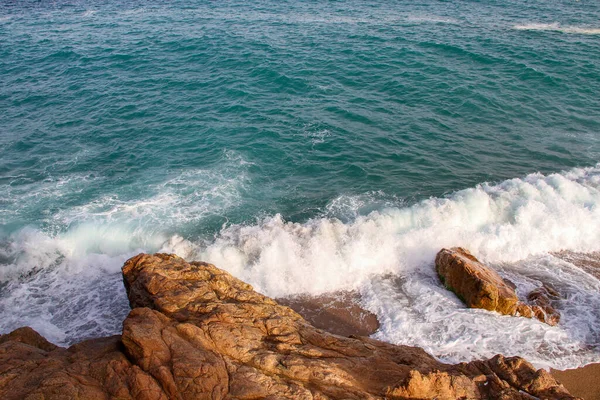 岩だらけの海岸にスプレーや泡の衝突を持つ海の波 — ストック写真