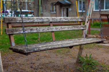 Evin bahçesinde zincire vurulmuş eski ahşap salıncak