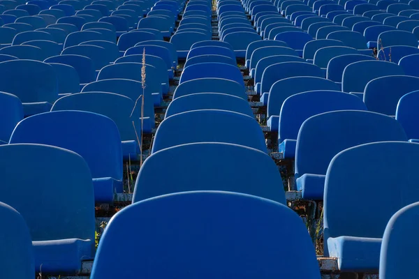 青いプラスチック製の椅子は古いスタジアムの列に立っています — ストック写真