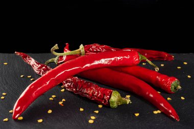 Siyah arka planda kırmızı biber kabukları. Tüketime hazır. Baharatlı yemek çeşnisi. Sağlıklı beslenme. Asya mutfağı.