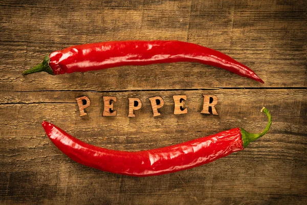 Chili Pepper on a wooden table, pepper seeds. Rustic style in a low key. Lettering in wooden letters.