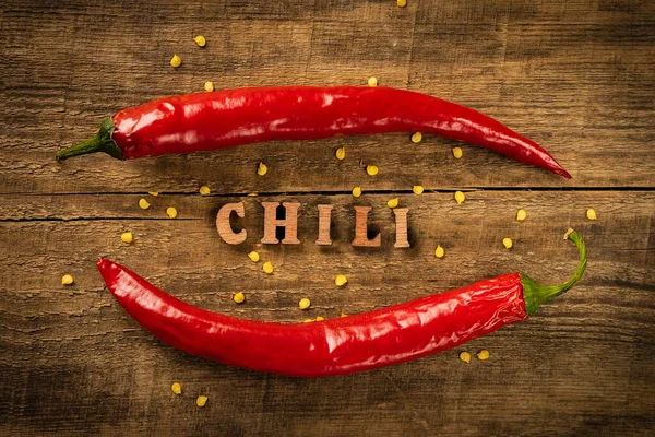 Chili Pepper on a wooden table, pepper seeds. Rustic style in a low key. Lettering in wooden letters.