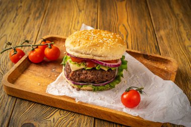 Ahşap bir masada ev yapımı lezzetli bir hamburger, köy usulü. Fast food. Metin için boşluk.
