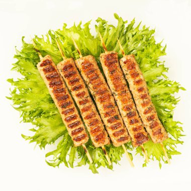 Chevapchichi, beyaz arka planda et aperatifi. Marul yaprakları et yemeğini tamamlar. Lula-Kebap. Seçici odak.