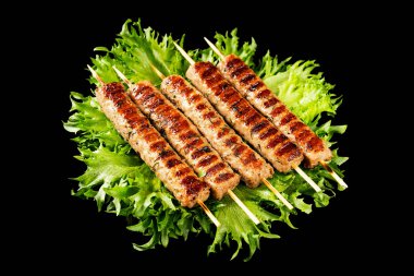 Chevapchichi, siyah arka planda et aperatifi. Marul yaprakları et yemeğini tamamlar. Lula-Kebap. Seçici odak.