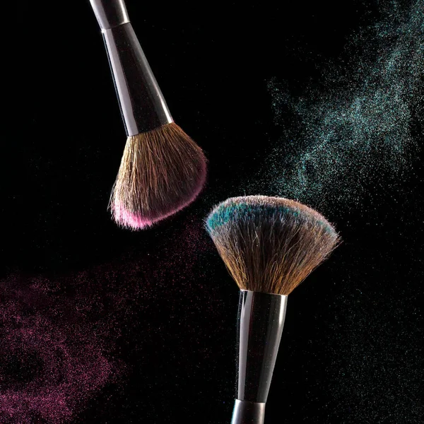 Makeup brushes, powder particles dynamically in the air. Spray cosmetics. Frozen dust, space simulation. Space for text.