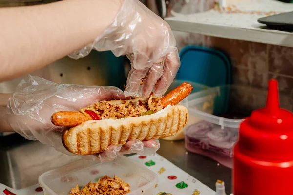 Danish hot dog. the process of preparing a Danish hot dog in the kitchen in a diner. Danish hot dog with fried sausage, ketchup, mustard sauce and raw and fried onions