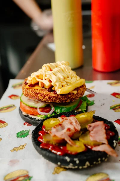 The process of making a chicken burger with fries in a black bun. The chef prepares a chicken burger with fries. Cooking burgers in the diner kitchen.