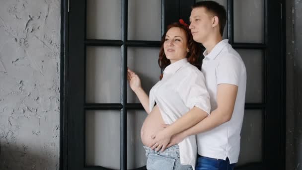 Young beautiful couple look to the side. Stand amid front of his house. — Stock video