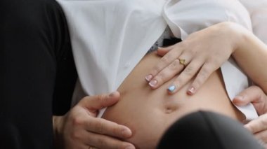 Pencerenin oturan yakışıklı genç adam. Çekici hamile karısını kucaklayan. Ağır çekim