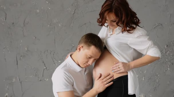 快乐的年轻人抚摸着他怀孕的妻子的肚子。年轻的妻子拍拍他的头. — 图库视频影像