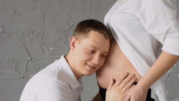 Заботливый счастливый молодой человек целует живот беременной жены. Медленное движение — стоковое видео