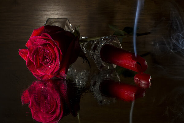 Red rose and red candle isolated on black background