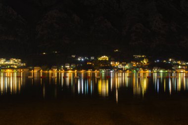 Gece Kotor Körfezi 'nin su yüzeyindeki ışık çizgileri. Karadağ 