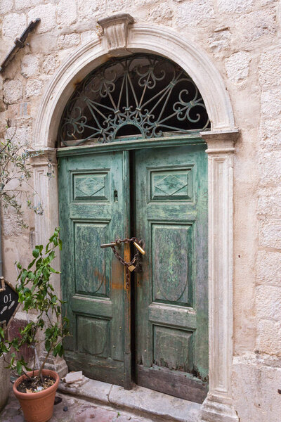 Ancient wooden green door on the street of the Old Town of Kotor. Montenegro