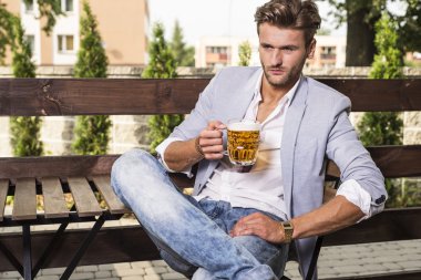Genç adam bira içiyor.